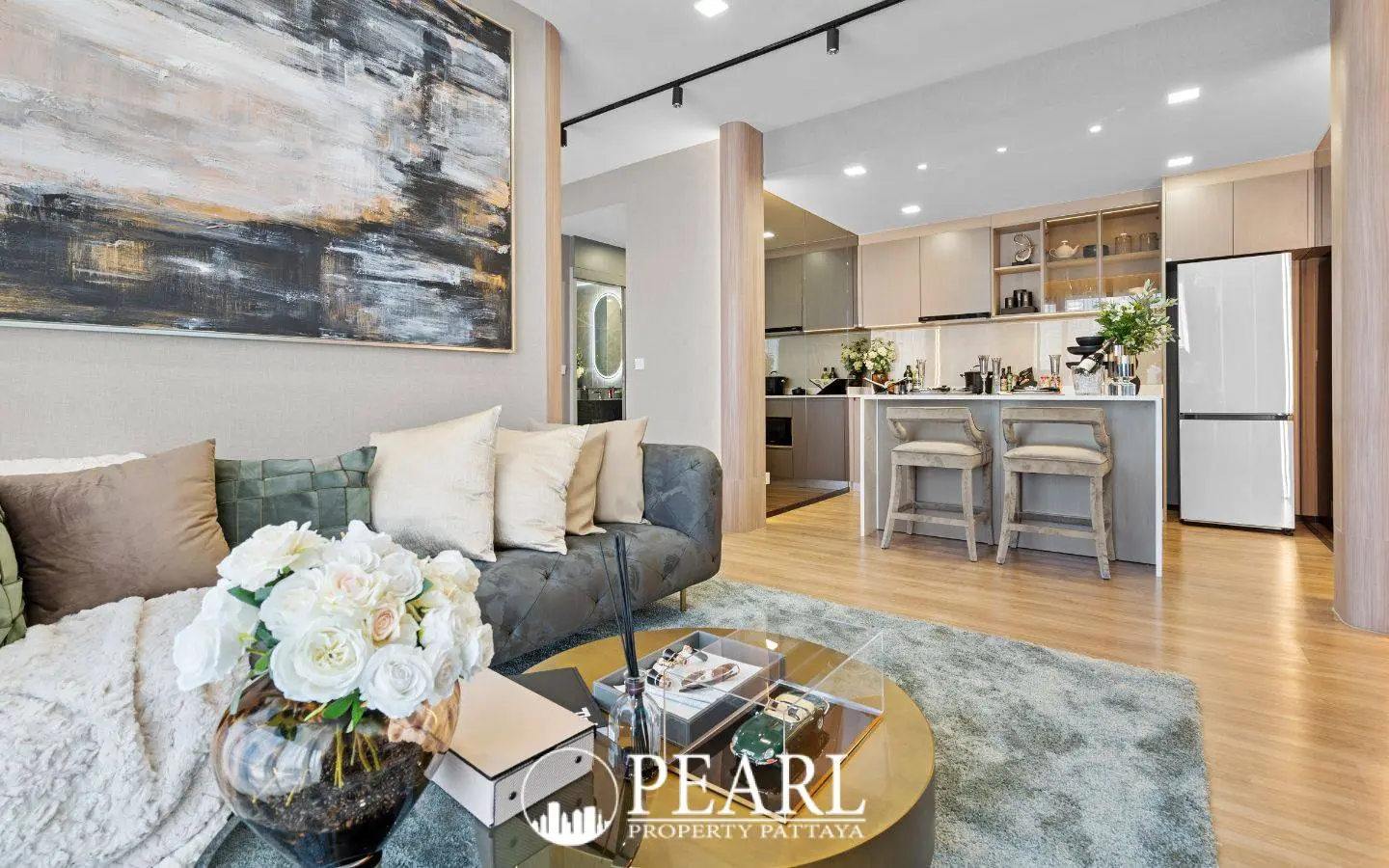 3 Bedroom Condo for Sale at Aquarous Jomtien Pattaya: Modern living room with sofa, coffee table, and open-plan kitchen with bar seating.