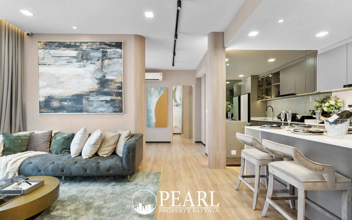 3 Bedroom Condo for Sale at Aquarous Jomtien Pattaya: Elegant living area with sofa, abstract art, and kitchen island with bar stools.