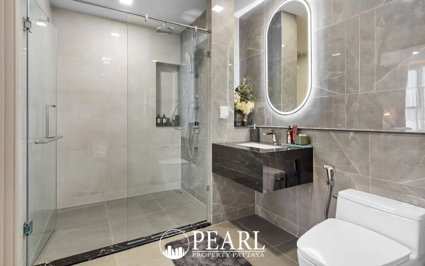 3 Bedroom Condo for Sale at Aquarous Jomtien Pattaya: Contemporary bathroom with glass shower, floating vanity, and illuminated mirror.