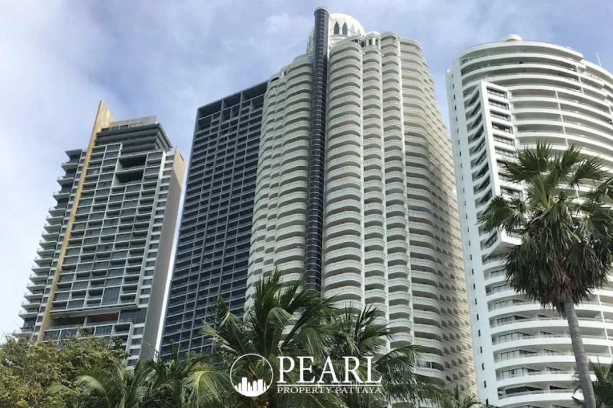Zire Wongamat three tall condo towers against a blue sky with palm trees in the foreground.
