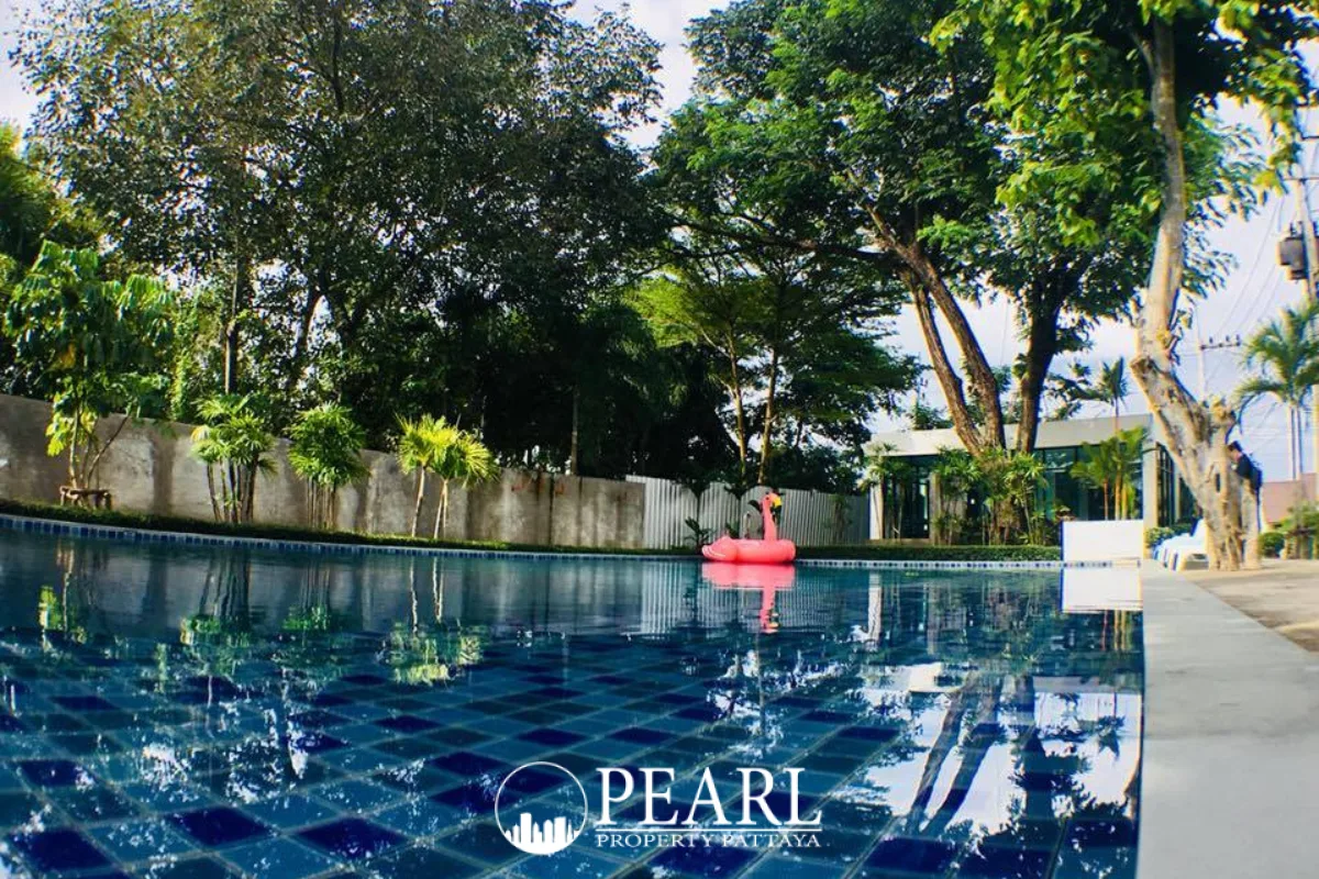 The Maple Pattaya outdoor swimming pool with a wooden swing structure and palm trees.