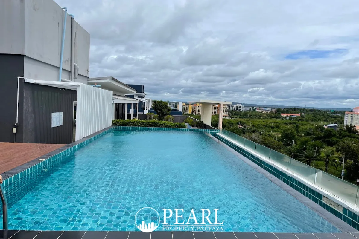 Neo Sea View: Rooftop infinity pool overlooking Pattaya cityscape, tall buildings, and the sea under a clear sky.