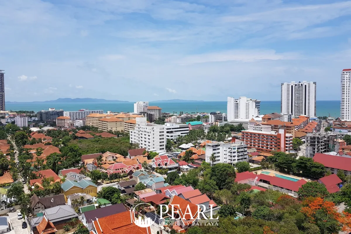 View Talay 2 aerial view of white condo buildings, parking lots, lush green trees, and Pattaya city skyline.