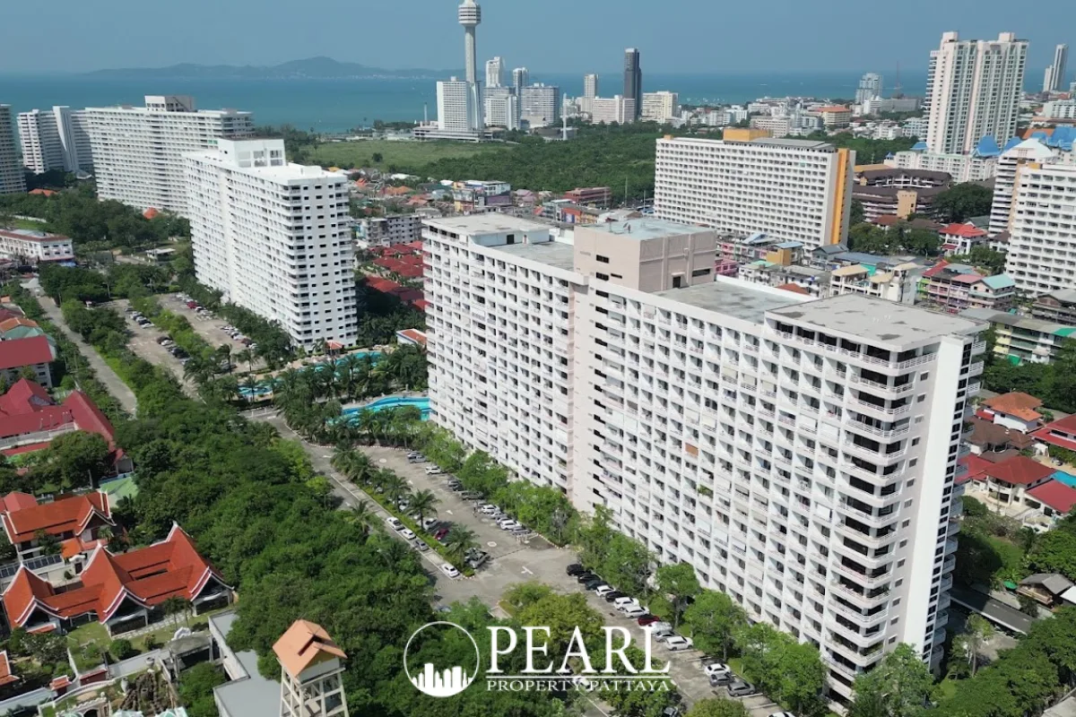 View Talay 2 aerial view of white condo buildings, parking lots, green trees, and Pattaya city skyline with ocean.