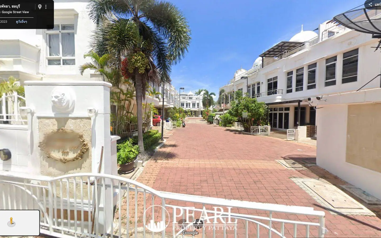 Wongamat Exclusive Place street view of the paved road leading into the residential complex with palm trees.