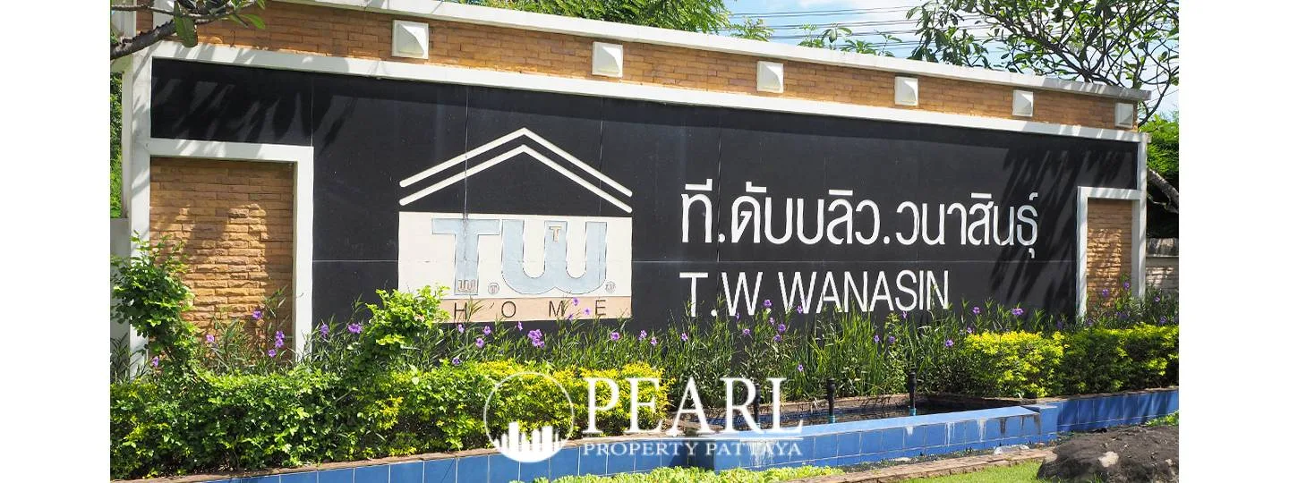 T.W. Wanasin property entrance sign with logo, name in Thai and English, and lush green landscaping.