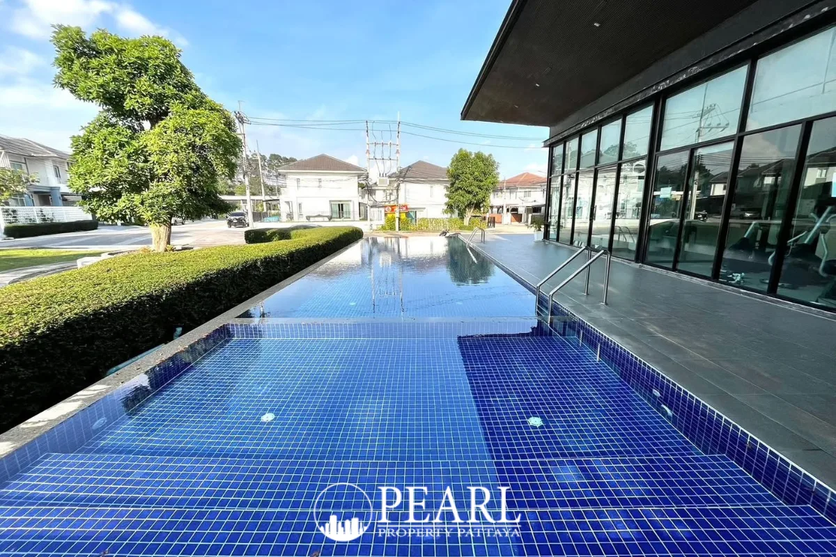 Baan Pruksa Nara Chaiyapruek outdoor swimming pool with blue tiles and a modern clubhouse building.