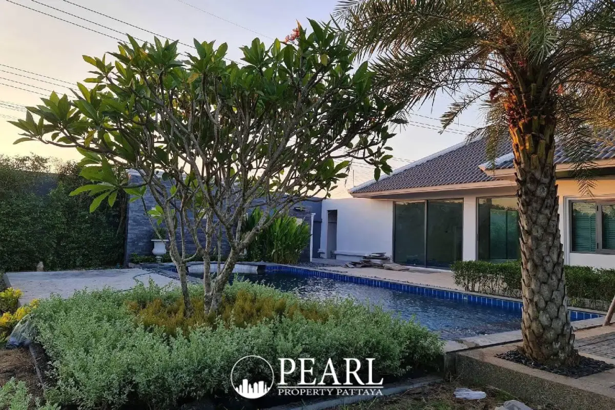 European Thai House exterior with large swimming pool, wooden deck, and palm trees under a blue sky.