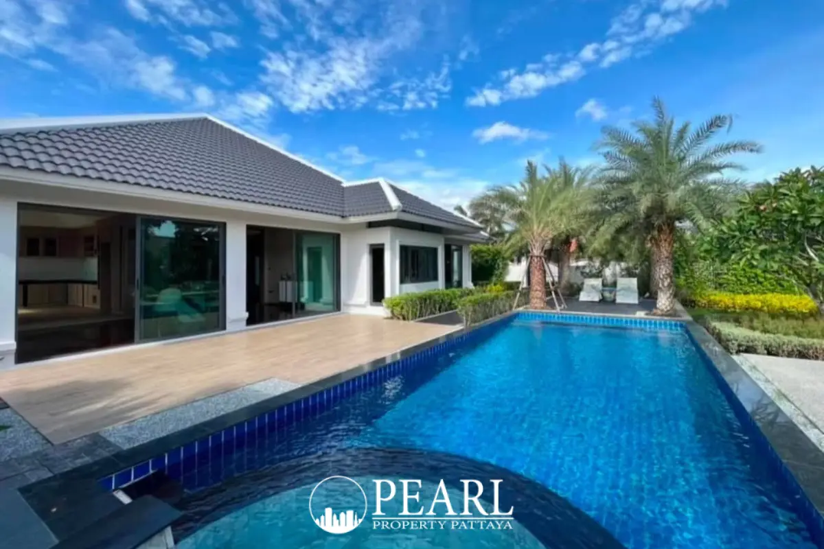 European Thai House exterior with large swimming pool, wooden deck, and palm trees under a blue sky.