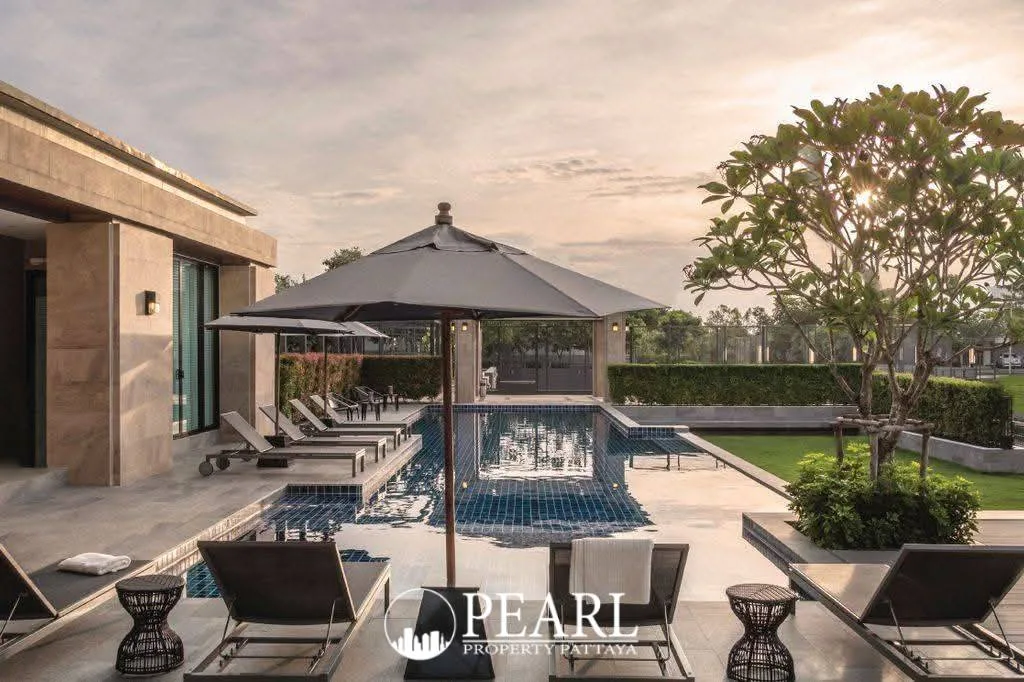 Patta Prime swimming pool area with sun loungers, umbrellas, and lush landscaping at sunset.