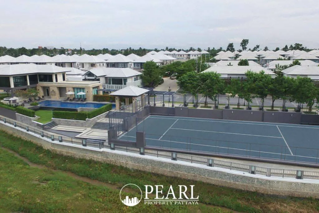 Patta Prime aerial view of the community with houses, a tennis court, and a large swimming pool.