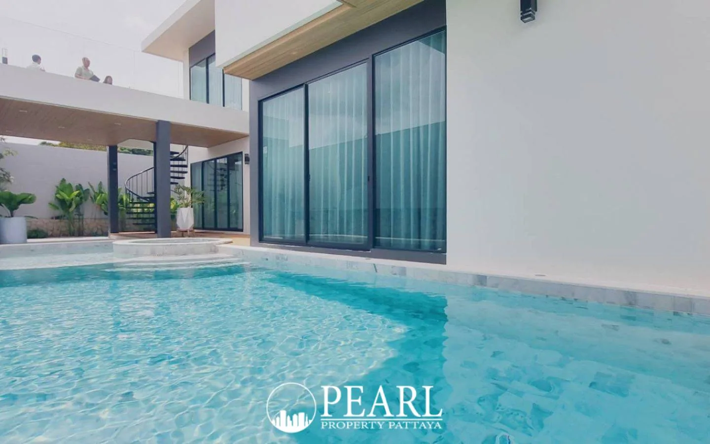 Manruetra Pura Pattaya front exterior of a modern house with covered parking and wooden accents under a bright sky.