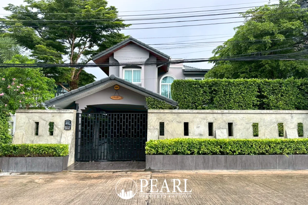 Phanthip Village 2 entrance sign in Thai and English, with a green restaurant building and a water tower in the background.