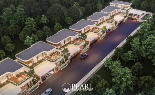 Charin Pattaya aerial view of a row of modern houses with balconies, carports, and a road, surrounded by lush trees.