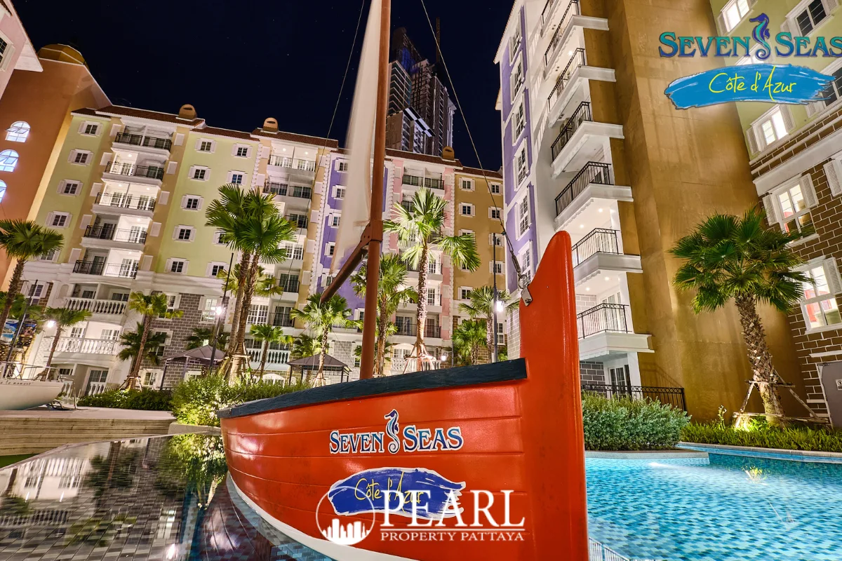 Seven Seas Cote d'Azur: Red decorative sailboat in a swimming pool at night, with colorful condo buildings in the background.
