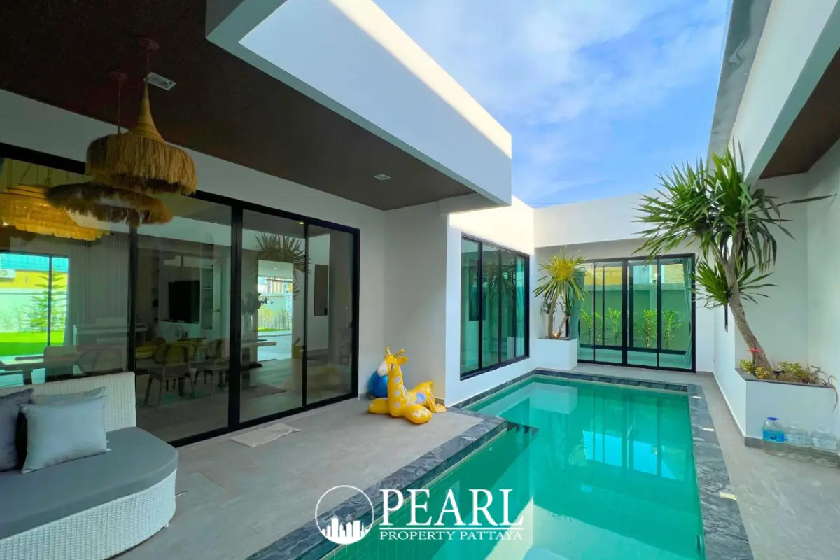 Baan Mae 2 Villa front exterior showing a large brown garage door, wooden entrance door, and modern peaked roof.