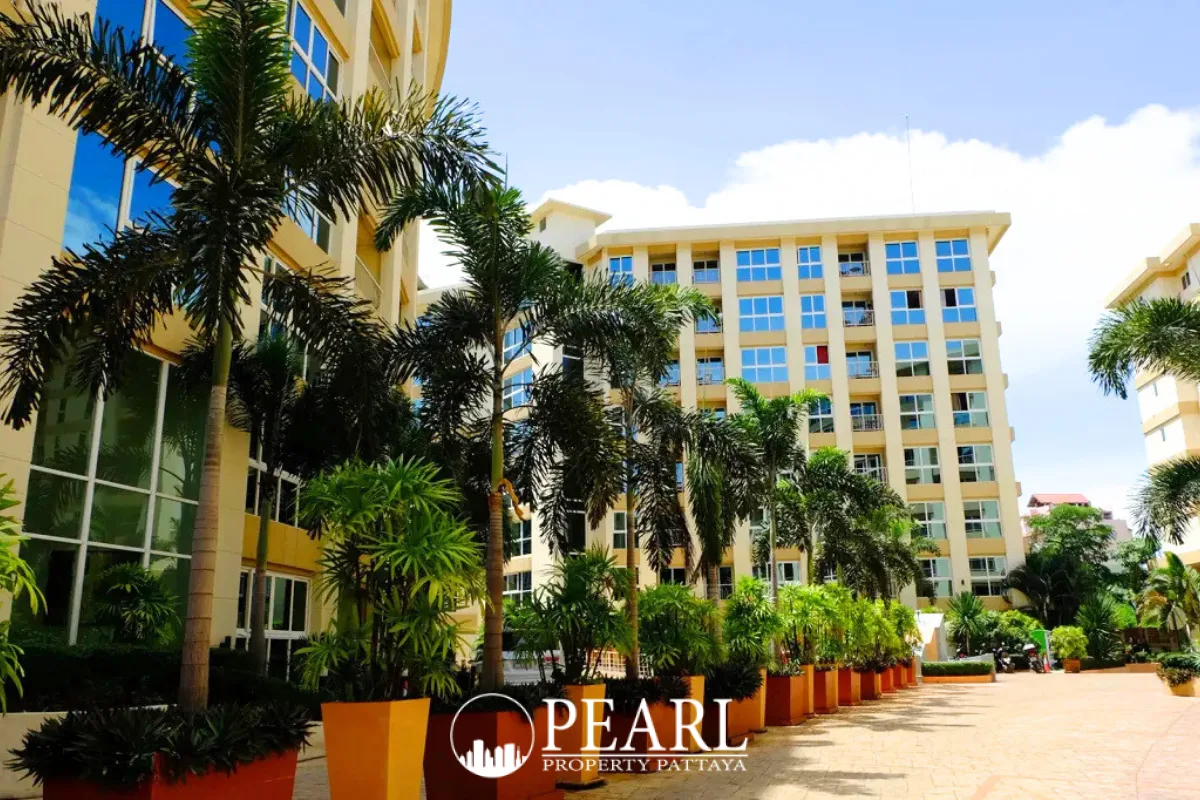 City Garden Pattaya outdoor swimming pool area with sun loungers, umbrellas, and curved apartment buildings.