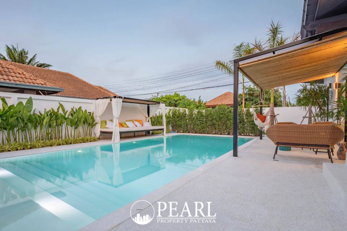 Srisuk Villa private swimming pool with outdoor daybed, lush green plants, and a shaded seating area.