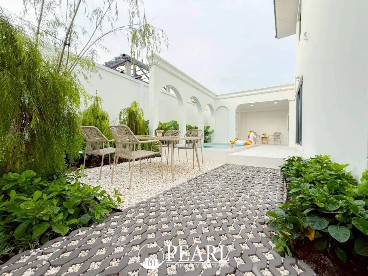 Spring Town Pool Villa Pattaya two-story house with a white facade, black balconies, and a covered parking area.