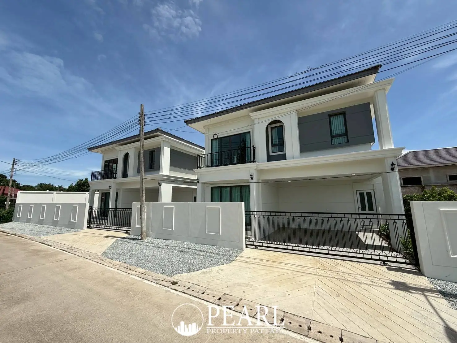 Spring Town Pool Villa Pattaya exterior view of two modern houses with gray and white facades under a blue sky.