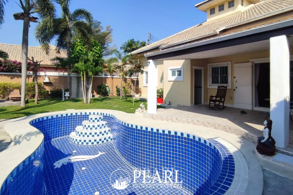 Classic Villa front entrance with a white ornate door, covered porch, and lush tropical landscaping.