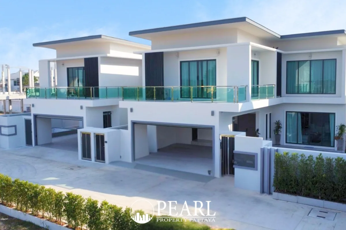 Jin Village modern white houses with flat roofs, balconies, and integrated carports under a blue sky.