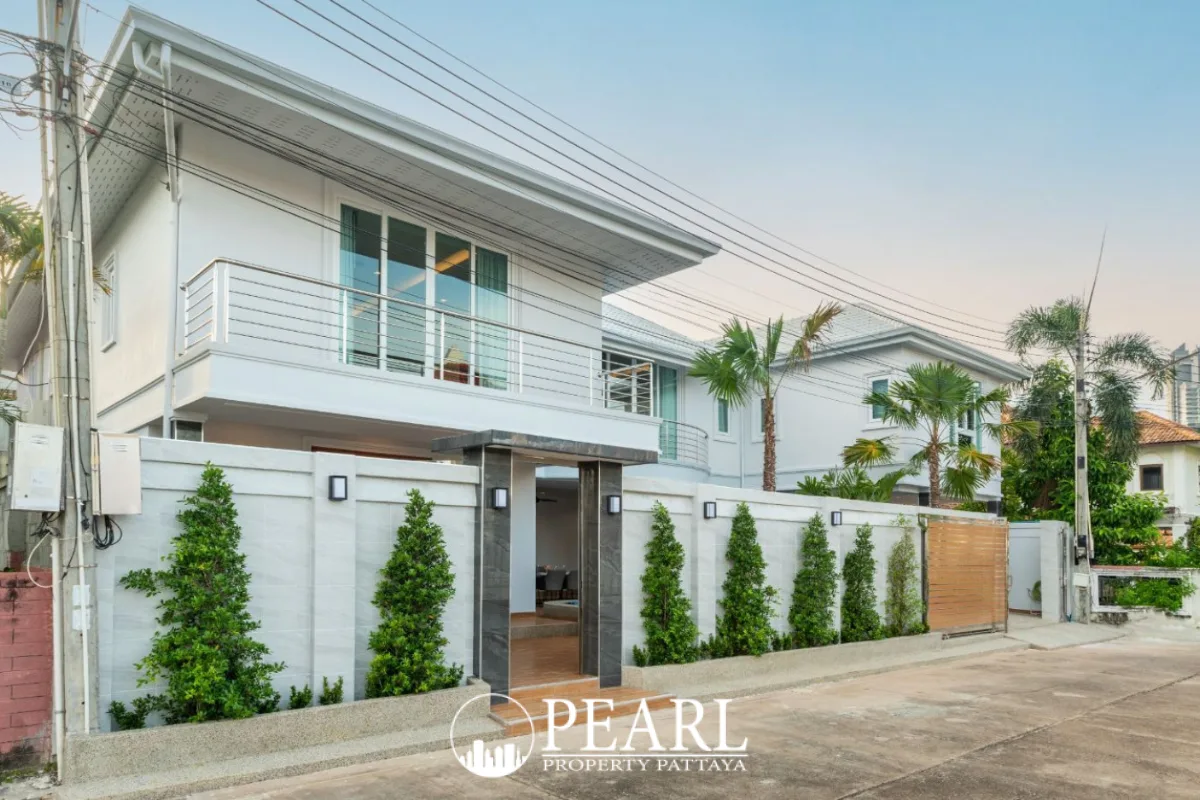 Pattaya Lagoon Village front exterior of a two-story white house with balcony and fenced yard.