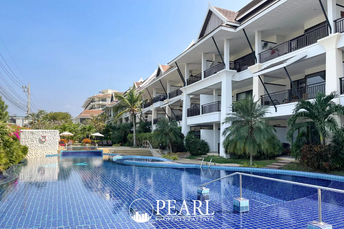 Sunrise Beach Residence outdoor swimming pool with blue mosaic tiles, bordered by a multi-story building and palm trees.