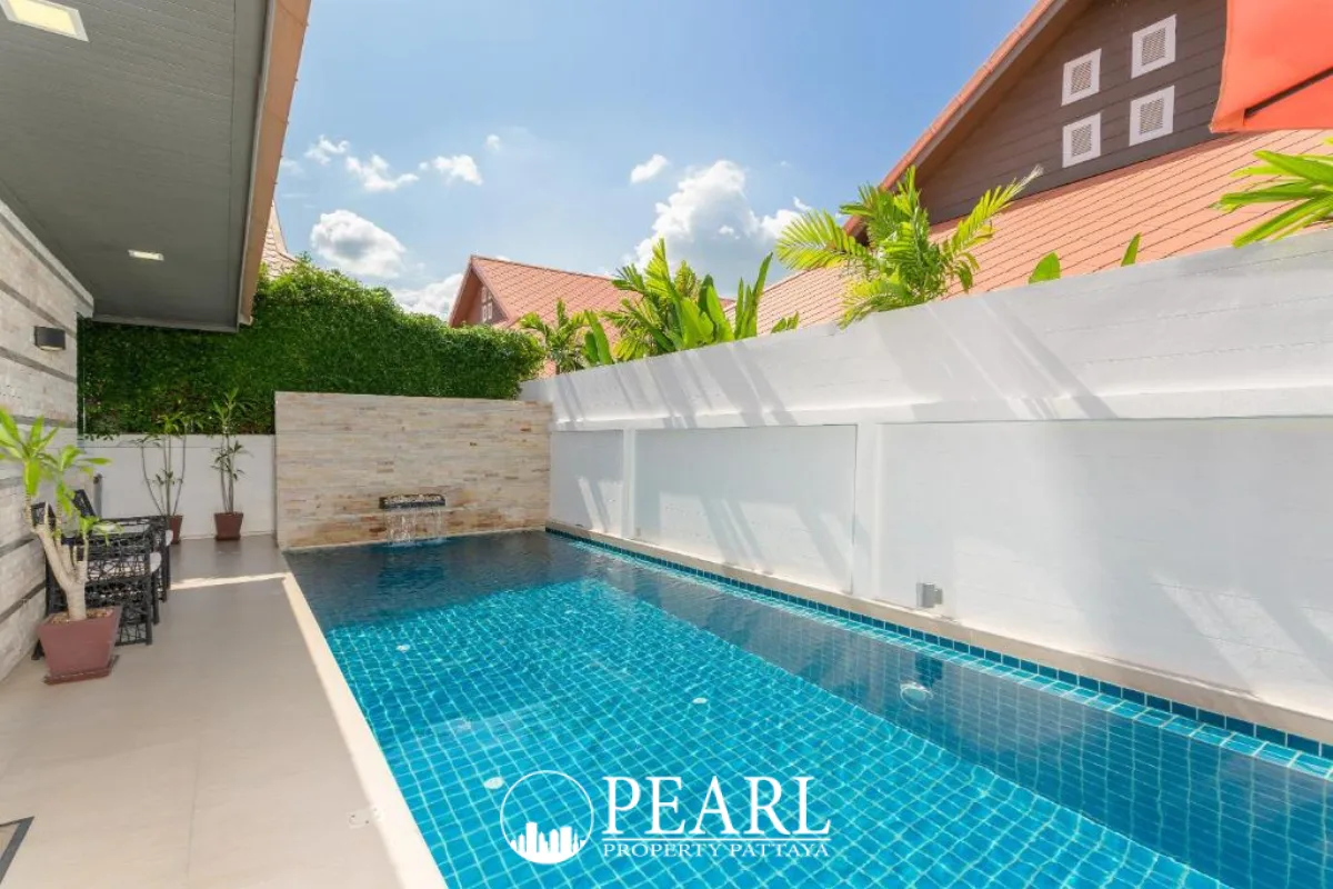 The Ville Jomtien main entrance gate with large stone sign under a clear blue sky.