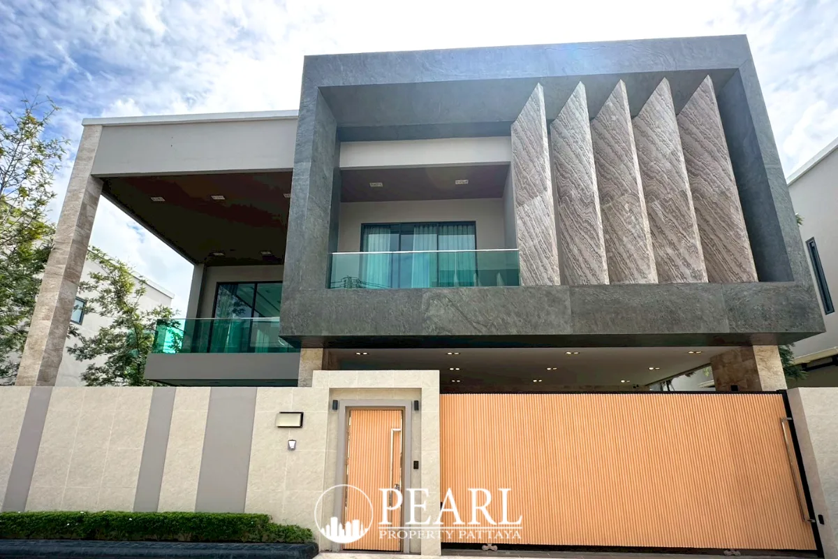 Madcha Nirvana modern house exterior with a grey facade, large windows, and a light orange gate.