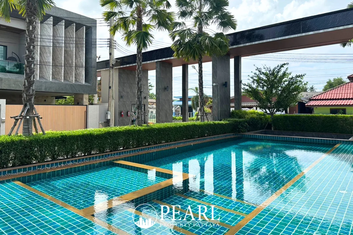 Madcha Nirvana communal swimming pool with blue tiles, surrounded by green hedges and modern architecture.