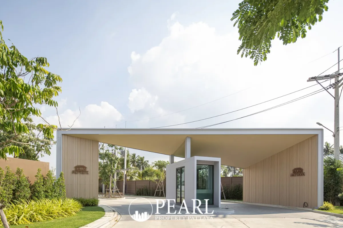 Baan Pattaya 6 modern entrance gate with security booth and lush landscaping under a bright sky.