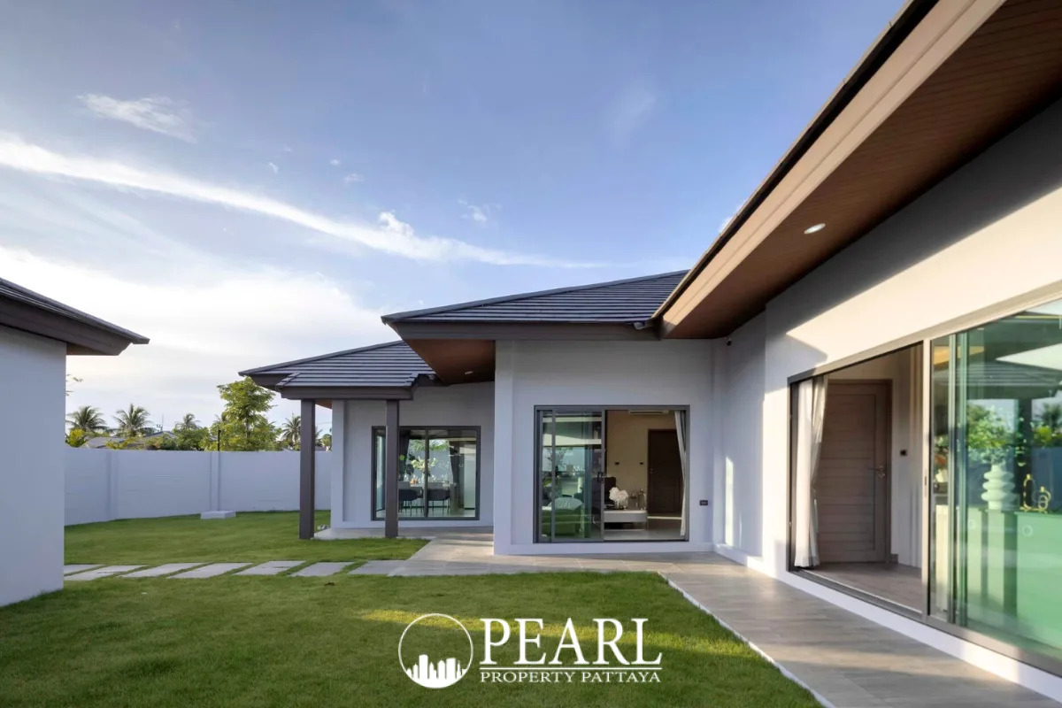 Baan Pattaya 6 modern clubhouse with a gym, illuminated at dusk, next to a swimming pool.