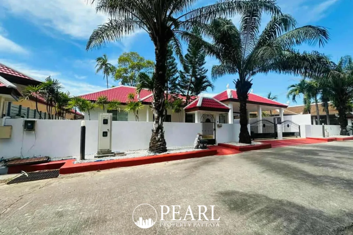 Paragon Park Village street view with white houses, red roofs, palm trees, and a gated entrance.