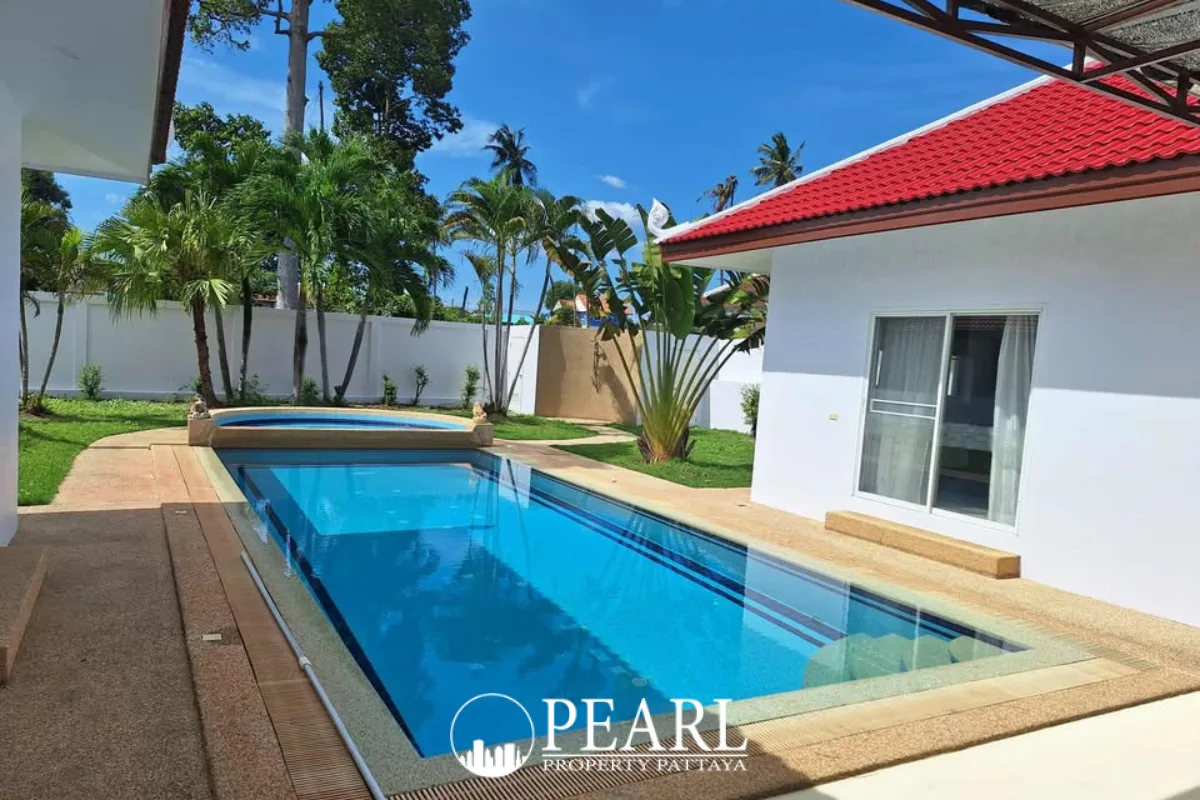 Paragon Park Village street view with white houses, red roofs, palm trees, and a gated entrance.