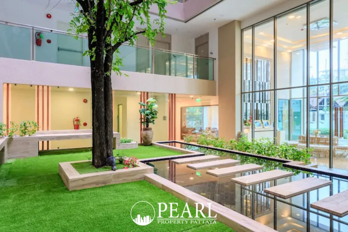The Cloud indoor garden atrium with a large tree, water feature, and artificial grass.