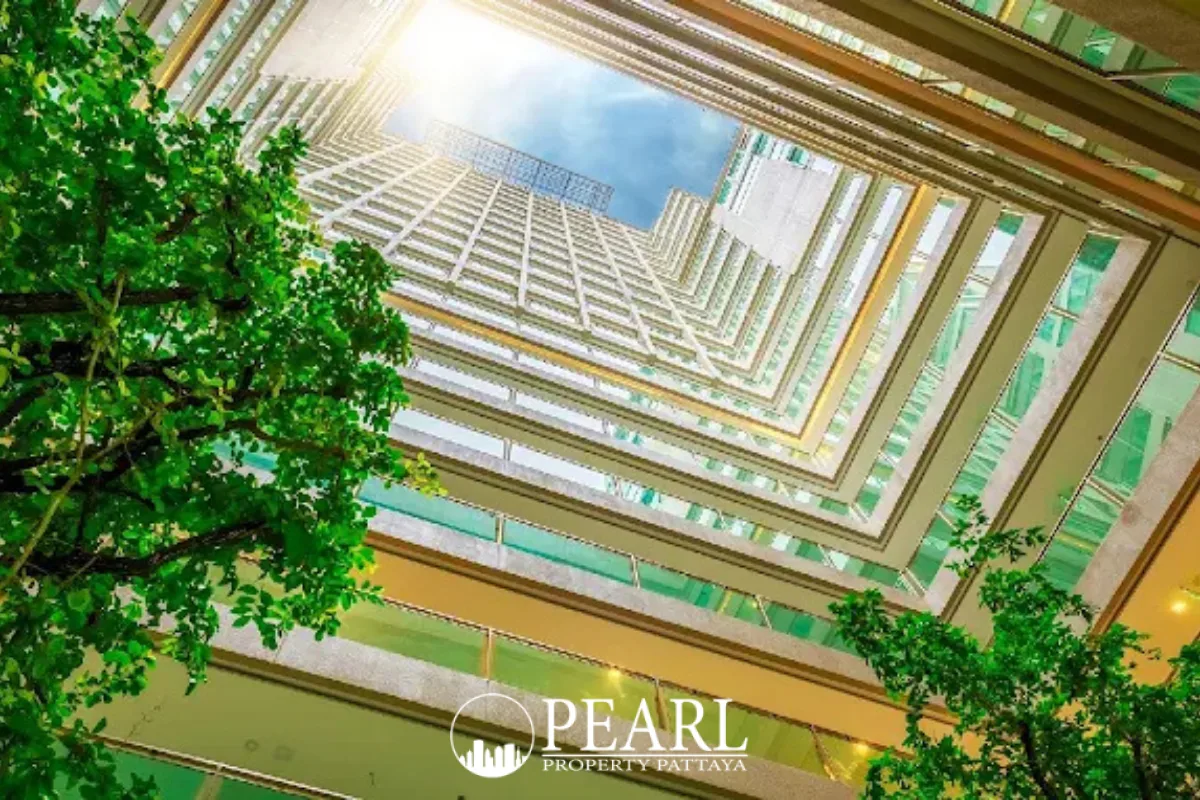 The Cloud looking up at the high-rise building's interior courtyard with bright sunlight and green trees.