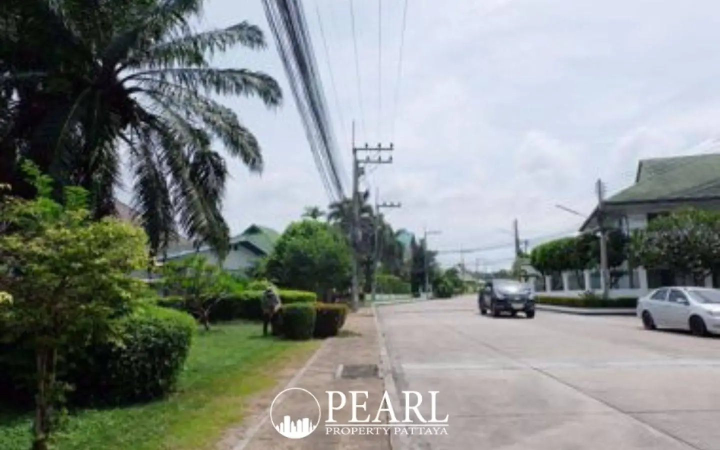 Baan Suan Suwattana Phase 2 entrance gate with security booth and barrier, leading to a residential street.