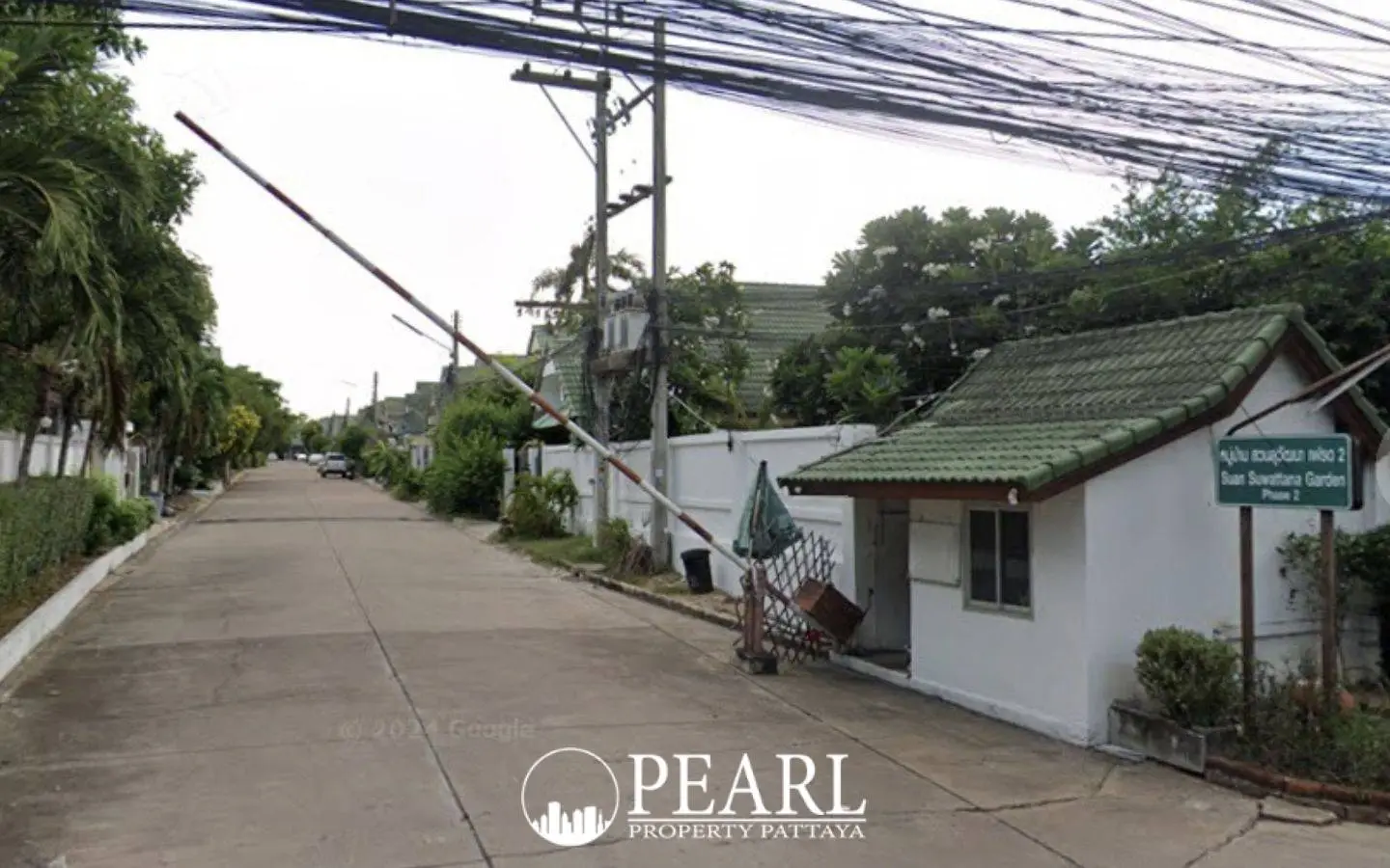 Baan Suan Suwattana Phase 2 entrance gate with security booth and barrier, leading to a residential street.