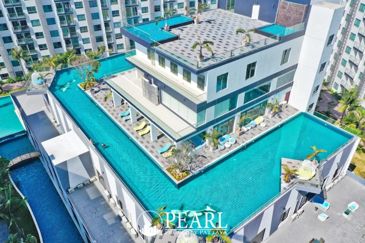 Arcadia Beach Resort expansive outdoor swimming pool area with sun loungers, surrounded by modern resort buildings.