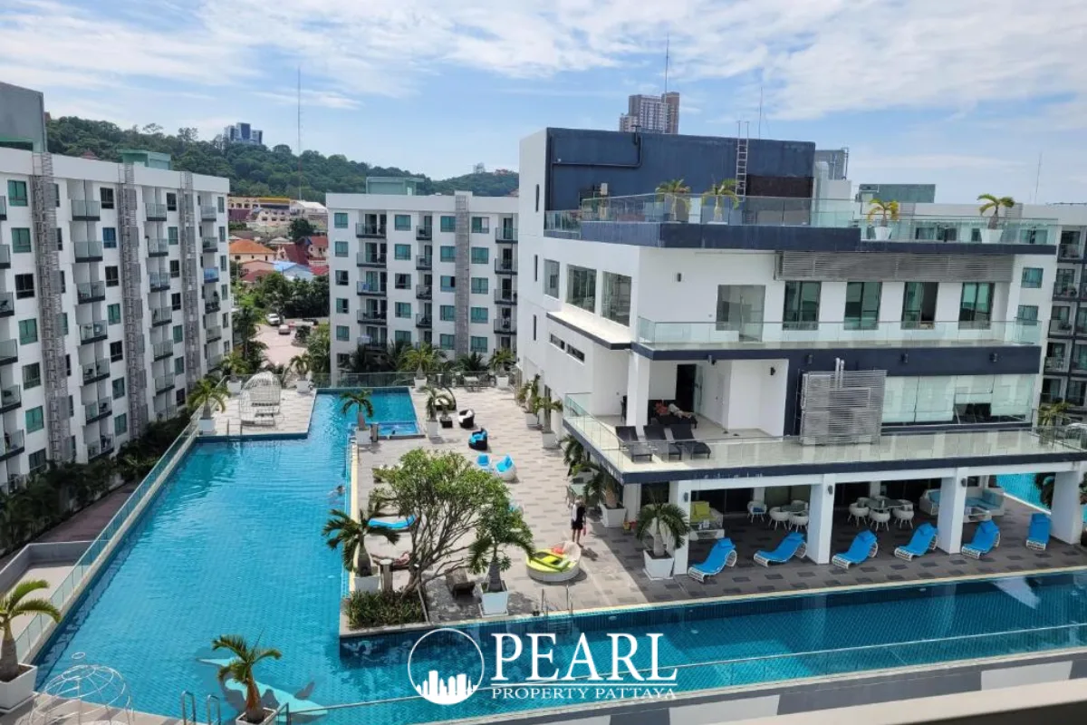 Arcadia Beach Resort main entrance sign with golden letters, lush greenery, and resort buildings in the background.