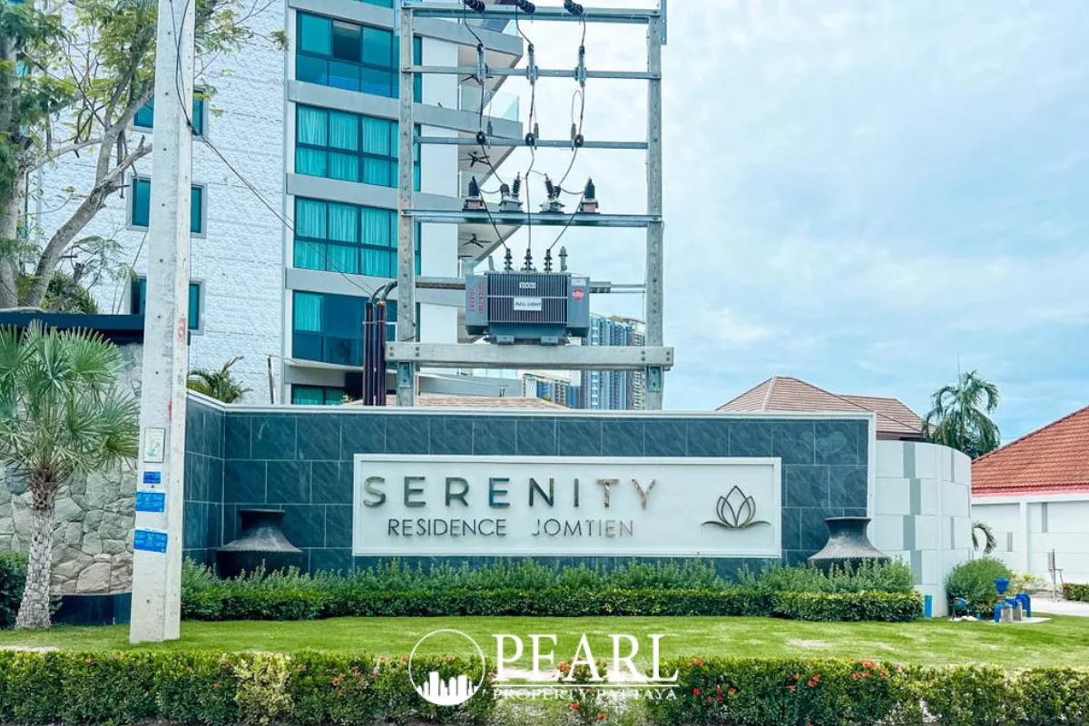 Serenity Residence Jomtien outdoor swimming pool with tiled bottom and the white apartment building facade.