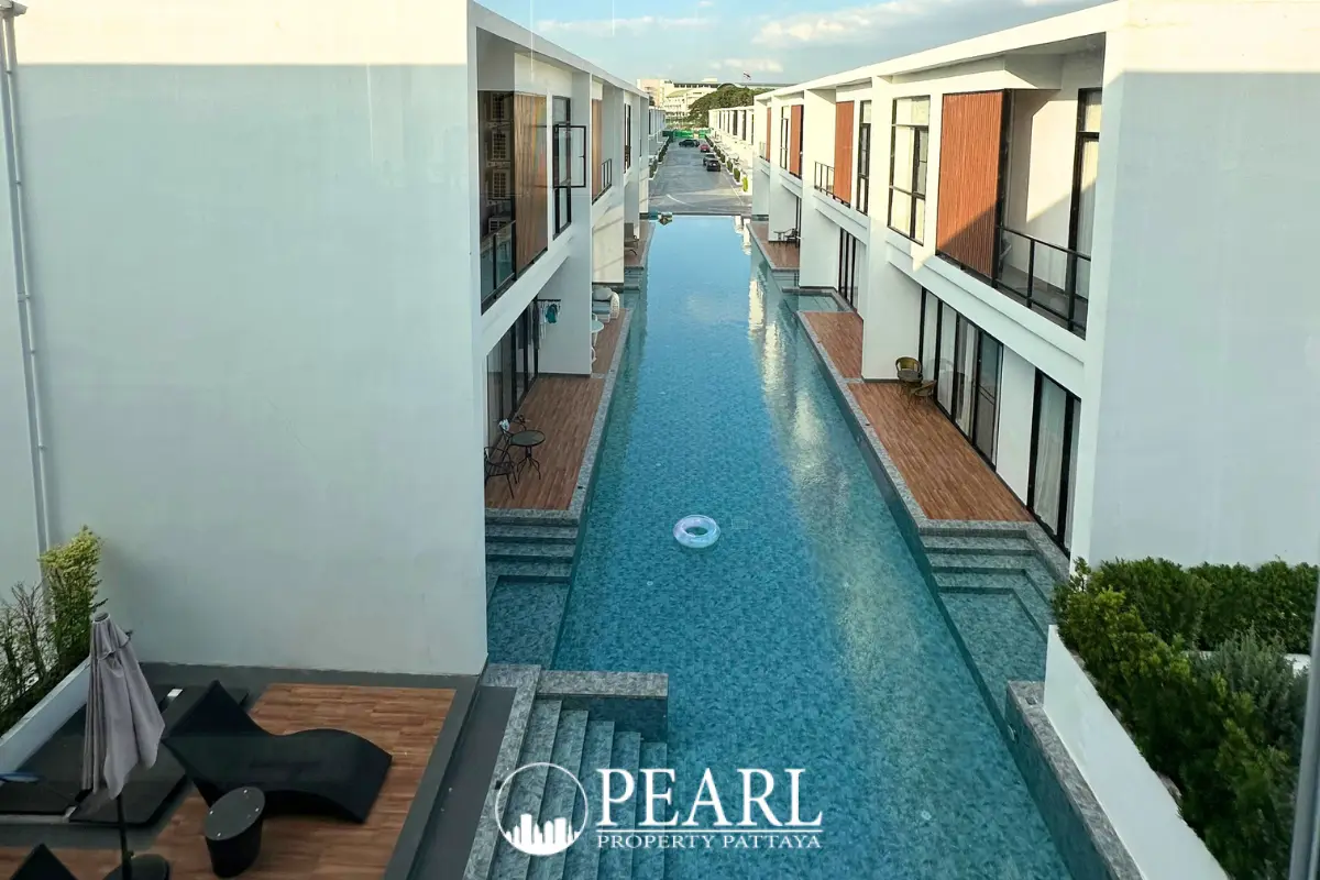 The Rich Garden long communal swimming pool flanked by modern townhouses with private wooden decks.